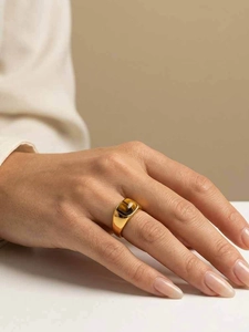 Détail d'une bague en acier doré ornée d'une pierre œil de tigre rectangulaire au doigt