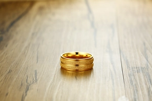 Macro shot of 8mm wide men's gold titanium ring with sandblasted finish and polished grooves