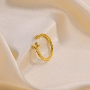 Macro shot of gold cross ring with cubic zirconia on beige silk fabric background