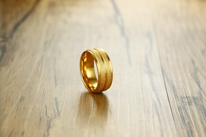 Close-up of 8mm gold titanium ring with a matte finish and parallel polished grooves
