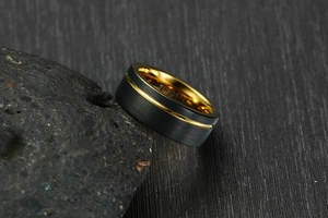 Macro detail of 8mm brushed black tungsten ring with gold groove and polished interior