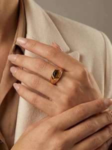 Détail d'une bague large dorée sertie d'une pierre œil de tigre de forme hexagonale
