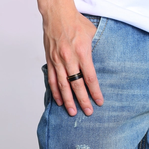Macro view of 8mm black brushed tungsten ring with gold groove worn on hand