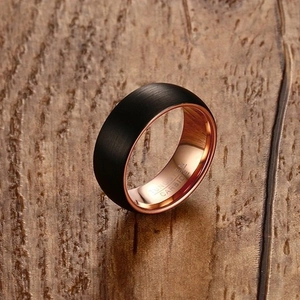 8mm black brushed tungsten carbide ring with polished rose gold inner band on wood