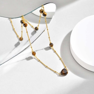 Gros plan d'un collier doré orné de perles œil de tigre et d'un pendentif en cœur