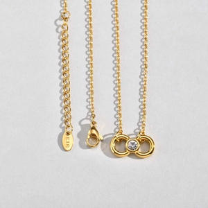 Détail du fermoir mousqueton et du poinçon K18 sur collier infini doré avec zircone