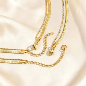Double-layered golden stainless steel snake and link chain necklace on silk background