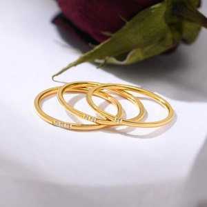Detail of three minimalist gold stackable rings with micro-pave crystals on white stand