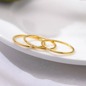 Close-up of three stacked 1mm gold-plated rings with tiny zircon stone inlays