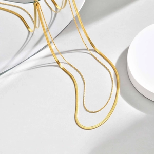 Detail of layered gold herringbone chain and delicate round link necklace set