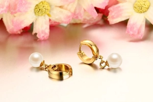 Macro view of 8mm pearl hoop earrings with polished gold finish and soft reflections