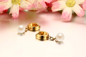 Detailed close-up of 8mm pearl drop earrings with elegant golden hoop and floral backdrop
