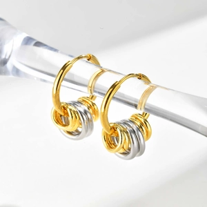 Detailed close-up of polished gold and silver interlocking rings on stainless earrings