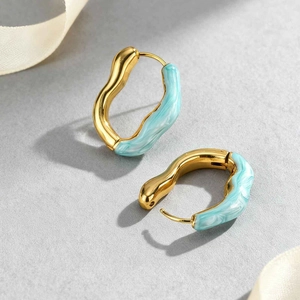 Détail macro de boucles d'oreilles vagues dorées avec texture marbre bleu clair