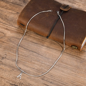 Silver stainless steel snake chain necklace with letter A pendant on leather notebook