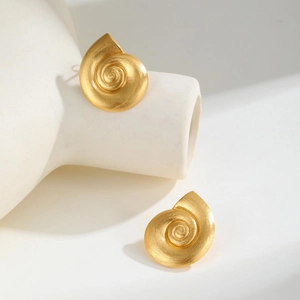 Macro shot of gold spiral conch stud earrings with a brushed matte metal finish