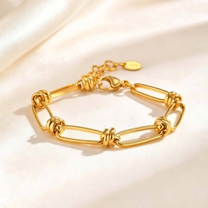 Macro detail of golden stainless steel link bracelet on soft cream silk backdrop