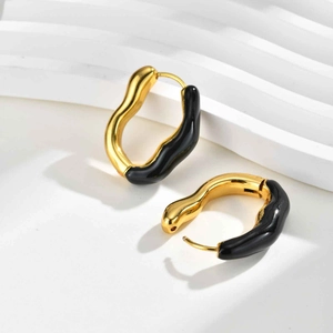 Vue détaillée des boucles d'oreilles vagues géométriques en métal doré avec émail noir