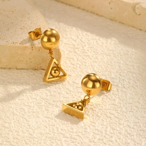 Close-up of geometric triangle gold earrings with dual beads on stone texture