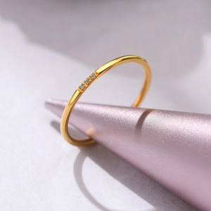 Macro view of a 1mm minimalist gold stainless steel ring with three inlaid cubic zirconia