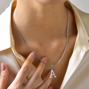 Close-up of letter A pendant on a silver square snake chain worn on a model's neck