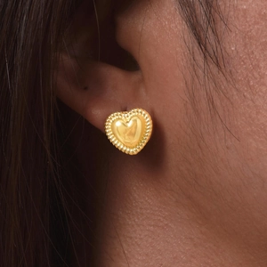 Close-up of 18K gold heart stud earrings featuring a twisted rope texture on a model