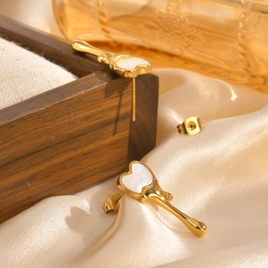 Gros plan sur boucles d'oreilles cœur doré avec nacre blanche et pendentif goutte d'eau