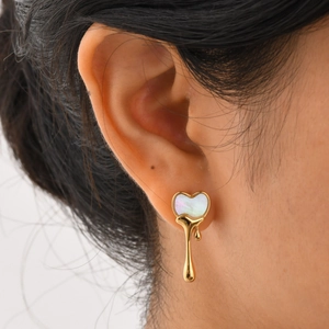 Gros plan sur la boucle d'oreille cœur doré fondu avec incrustation de nacre