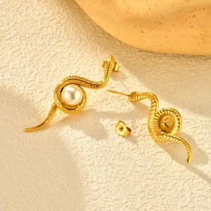 Détail de boucles d'oreilles serpent dorées avec perle et écailles sur fond blanc