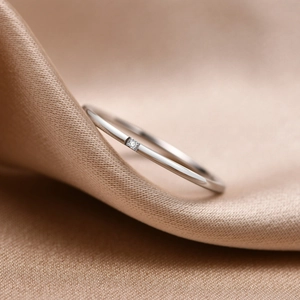 Macro view of a 1mm gold stainless steel ring with a square zircon on champagne silk