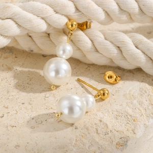 Boucles d'oreilles en acier doré avec trois perles blanches graduées sur socle en pierre