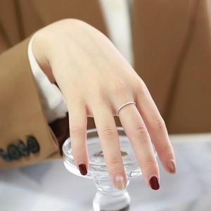 Macro detail of high-polish minimalist silver stackable ring on hand with blurred professional background