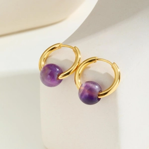 Elegant gold hoop earrings with round purple amethyst beads on white geometric stands