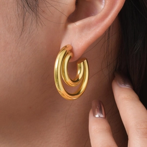 Gros plan d'élégantes boucles d'oreilles créoles doubles en C dorées 18K