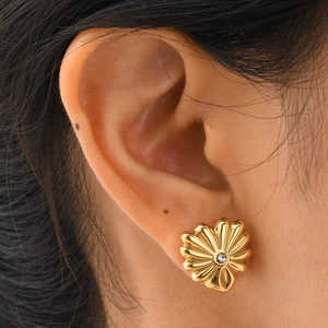 Gros plan sur un clou d'oreille fleur dorée avec zircon brillant sur l'oreille