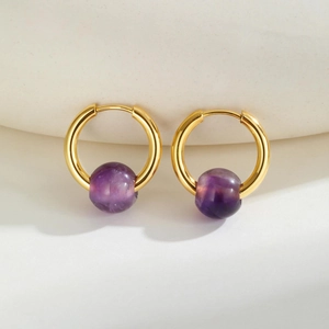 Detail of French style gold titanium earrings with purple amethyst beads and polished finish