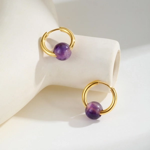 Close-up of gold titanium steel hoops with purple amethyst beads on white display