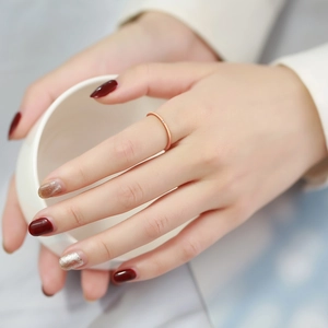 Detail of 1mm gold stacked ring with mini zircon on hand holding a white cup