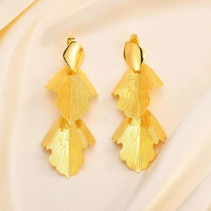 Detailed view of layered golden leaf tassel earrings on elegant silk background
