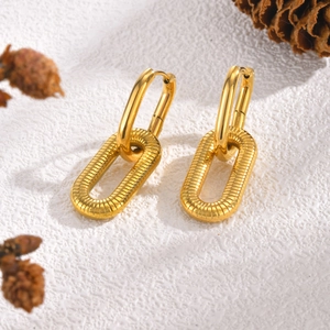 Detailed macro view of gold oval hoop earrings with textured rectangular charms