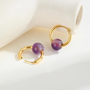 Detail of gold titanium hoop earrings featuring translucent purple amethyst beads