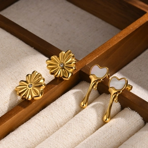 Clous fleurs dorés et boucles d'oreilles cœur fondant sur plateau d'exposition en bois
