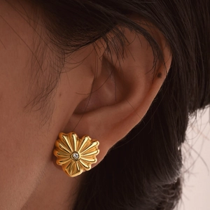 Boucles d'oreilles fleurs dorées avec cristal central portées par un mannequin