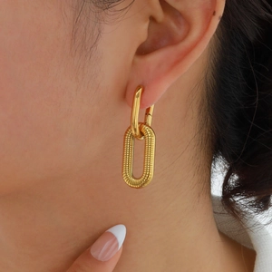 Detail of gold oval double hoop earrings featuring textured and smooth metal surfaces