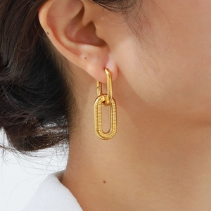 Close-up of gold-plated oval earrings with spiral texture on a female model's ear