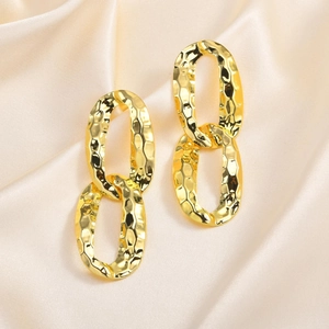 Golden hammer-textured geometric oval double-link drop earrings on soft champagne silk fabric