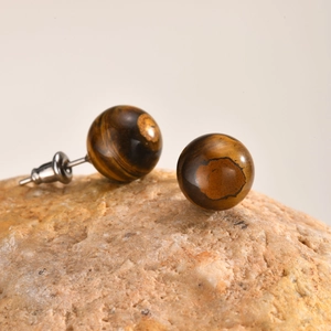 Detailed macro view of round tiger eye stone stud earrings with stainless steel pins