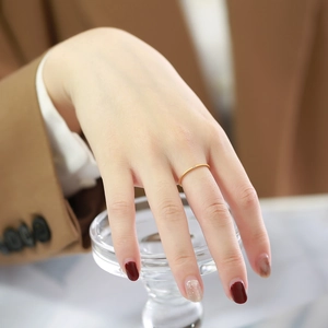 Detail of 1mm gold minimalist stainless steel ring with a single zircon on a finger