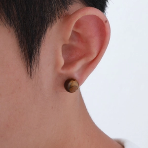 Detailed close-up of a natural tiger eye stone ball stud earring worn on the ear