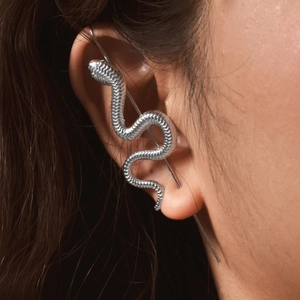 Détail d'un ear cuff serpent en acier inoxydable argenté avec texture d'écailles sur l'oreille